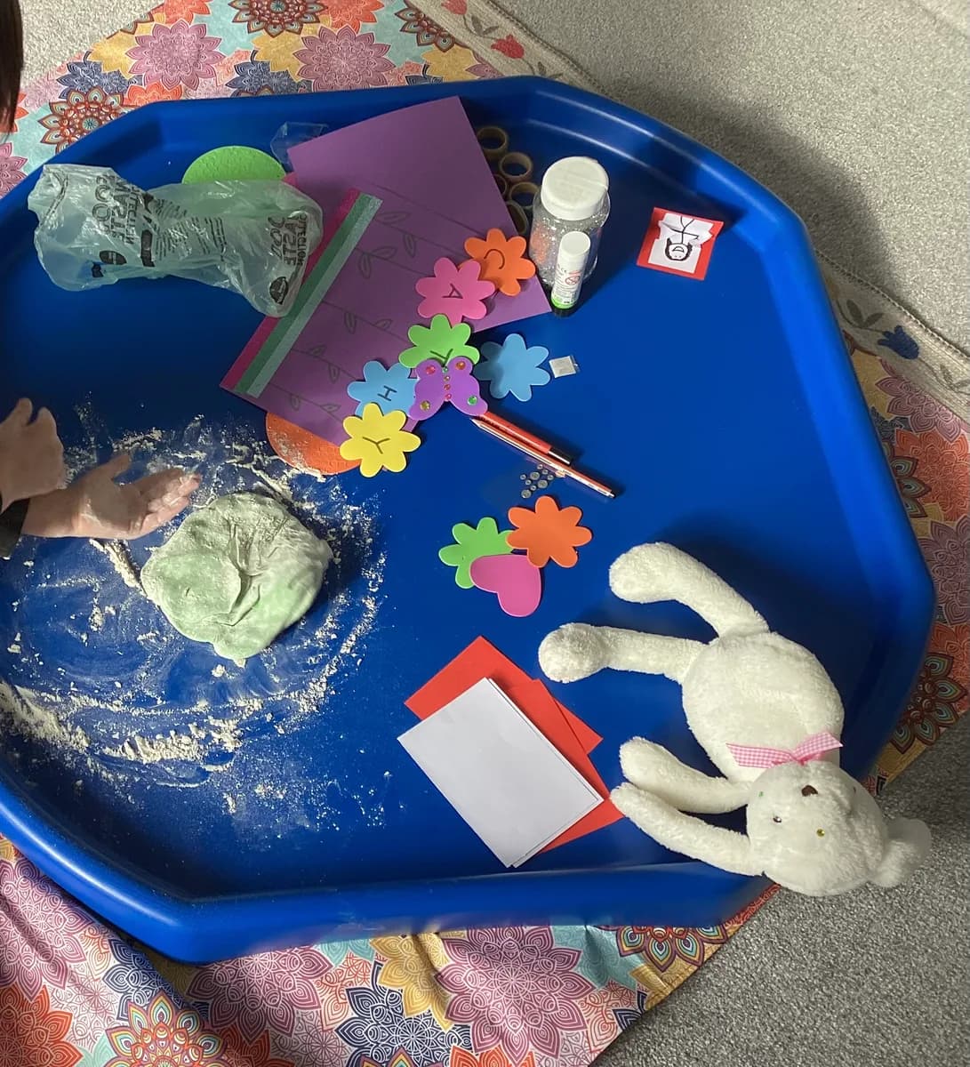 Dough, colourful foam flowers and craft materials on a blue activity tray