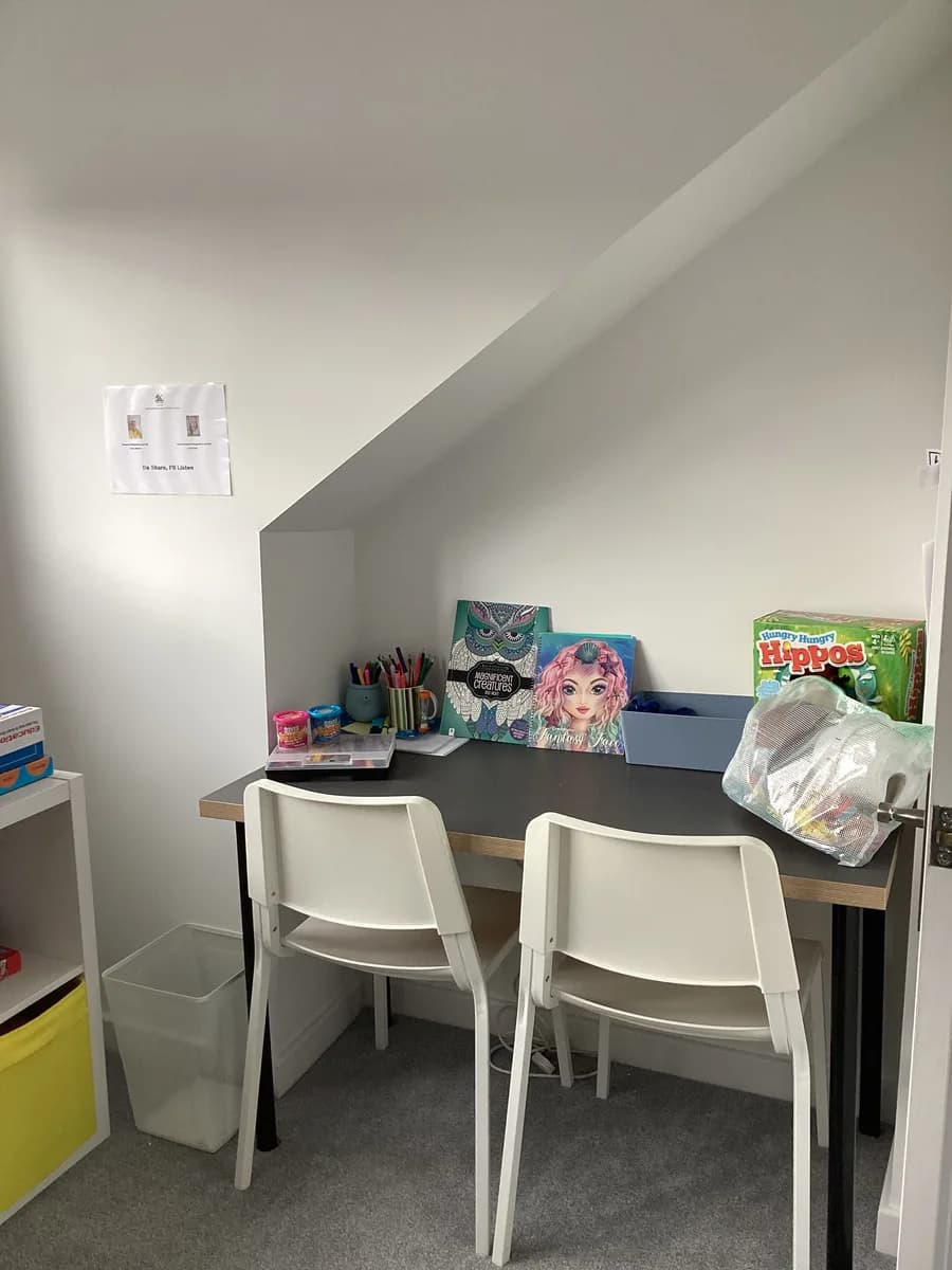 Two chairs at a desk with craft materials and tabletop games