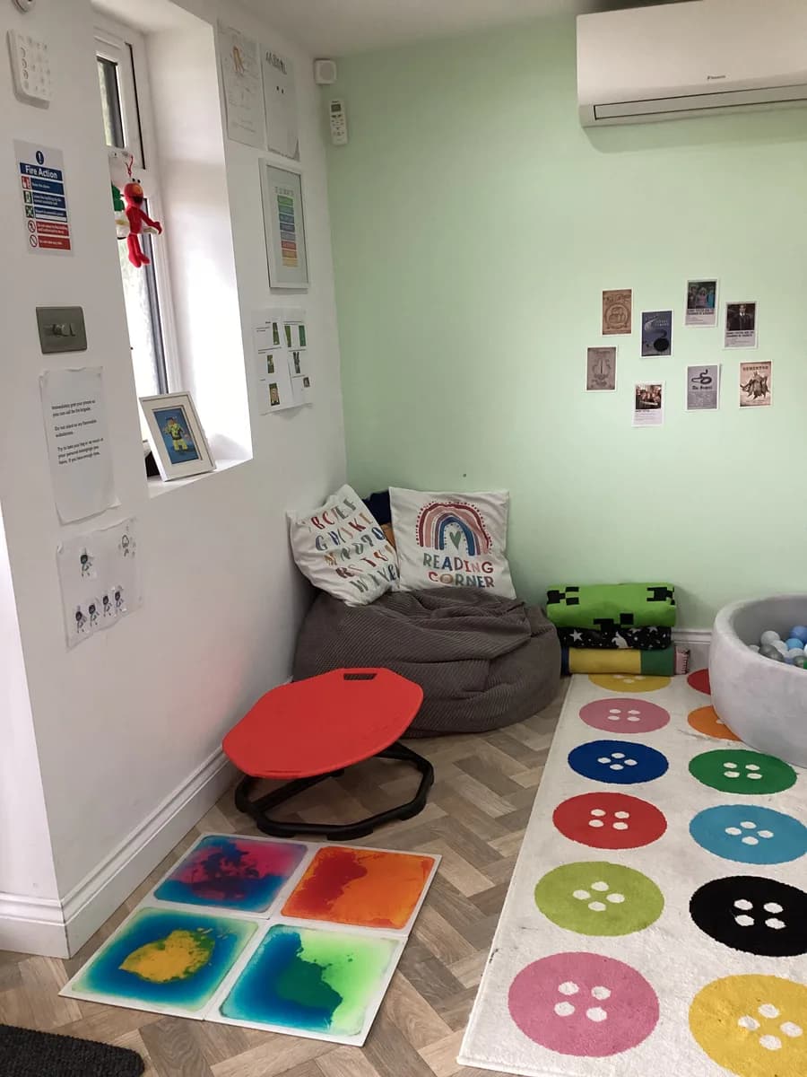 A reading beanbag beside a low red table and colourful sensory floor tiles